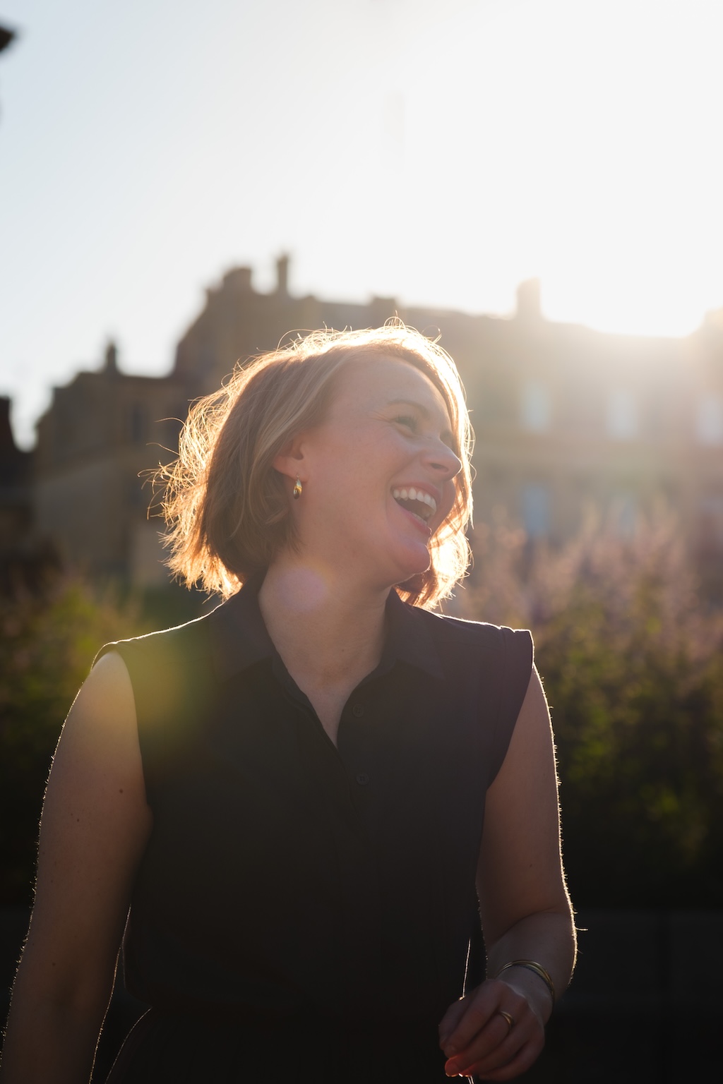Femme souriante dans les rues de Paris, lumière douce et tons chaud pendant le coucher du soleil
