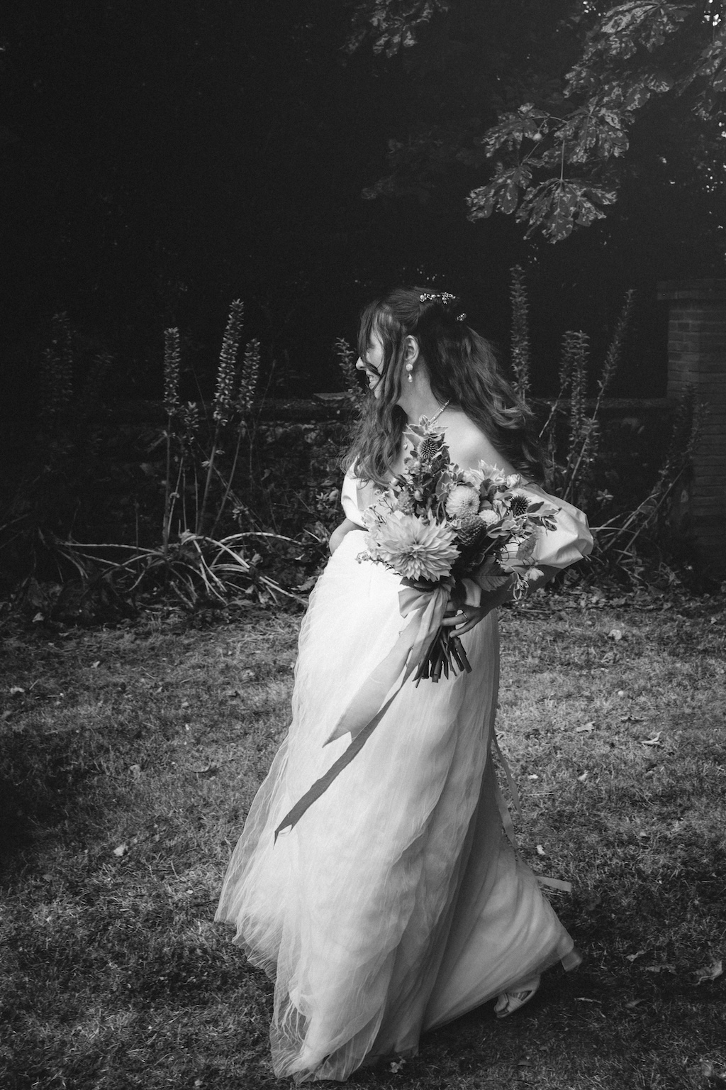 Mariéé avec son bouquet de fleur dans le jardin de la mairie pendant un reportage photo d'un mariage