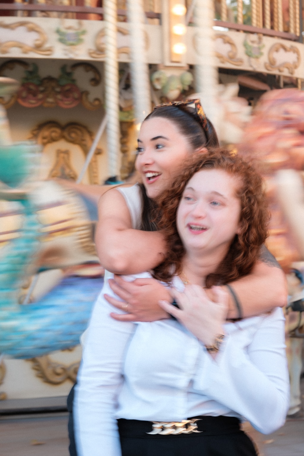 Couple de femme s'enlaçant devant un manège dans le centre de paris