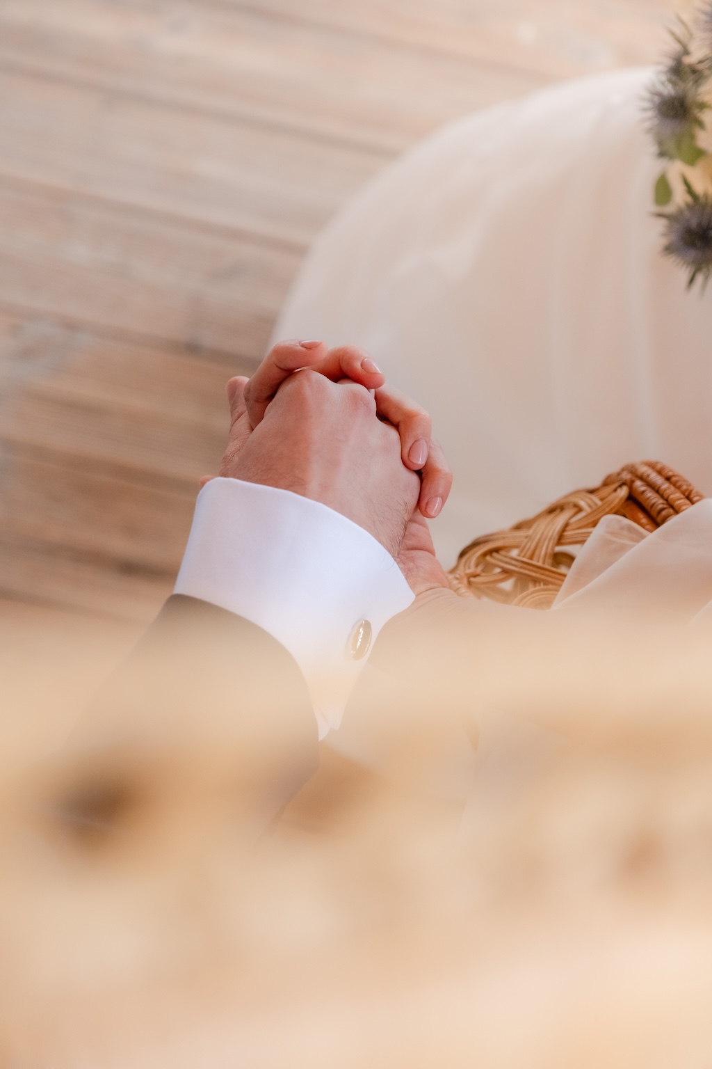 Gros plan sur les mariés se tenant la main pendant la cérémonie religieuse
