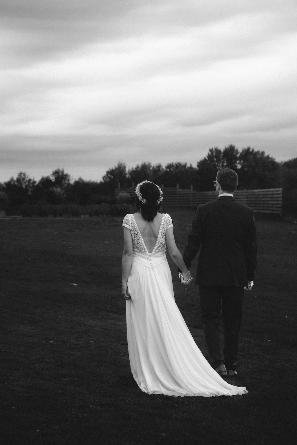 Des mariés se tenant la main et marchant dans le jardin du domaine de leur mariage à Paris