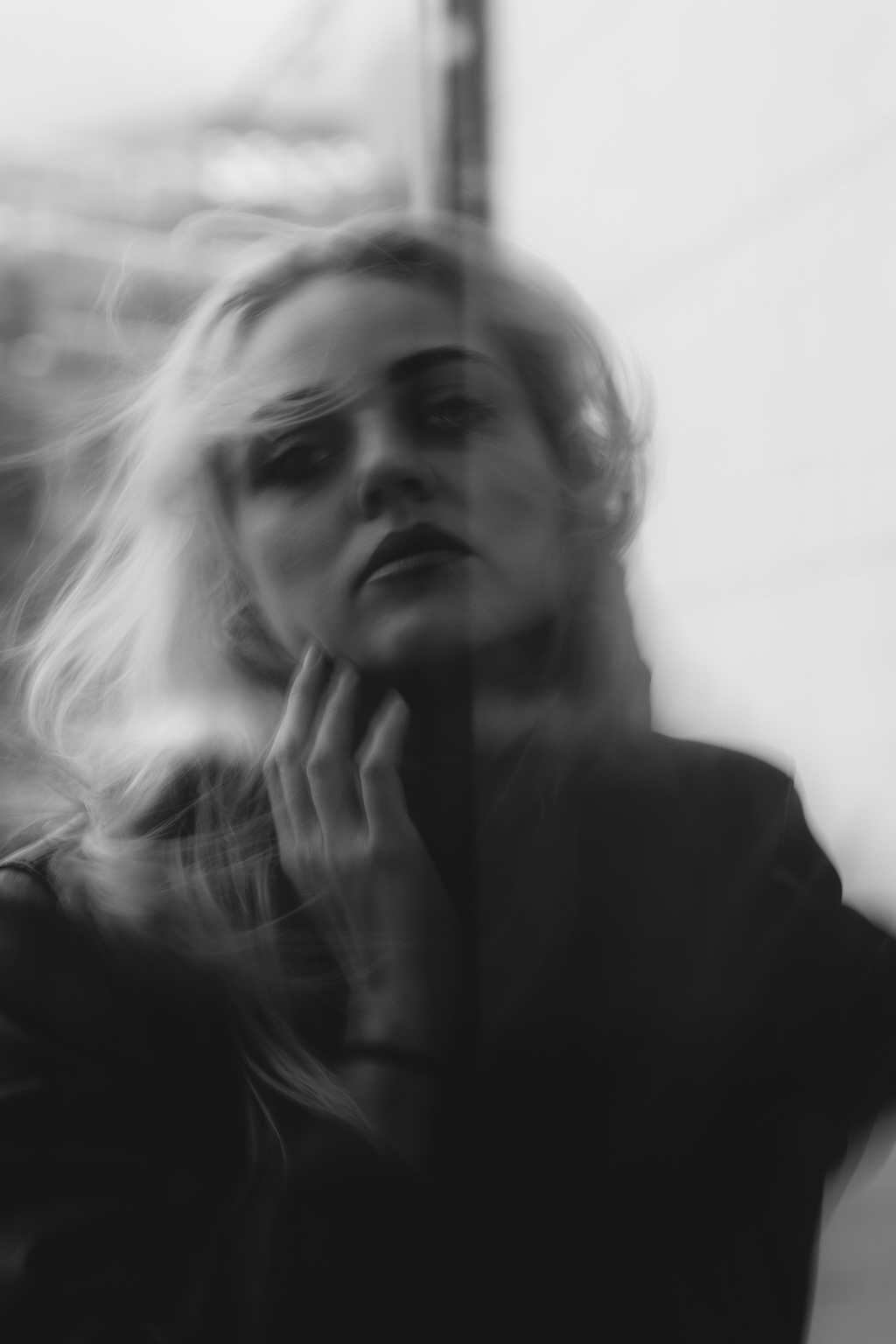 Portrait d'une femme de face se tenant le visage en fin de journée à Paris, lumière douce et traitement noir et blanc de l'image