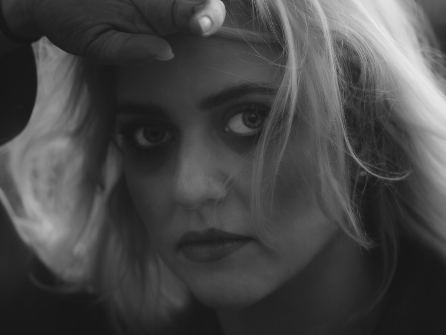 Portrait d'une femme de face se tenant les cheveux, traitement noir et blanc