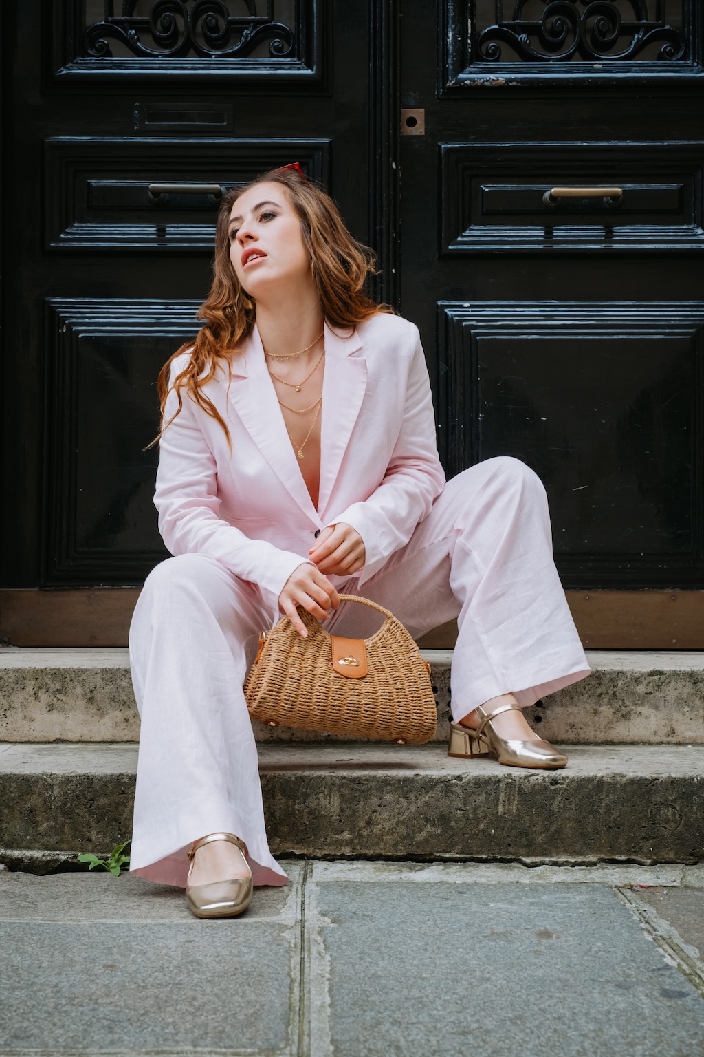 Portrait d'une femme en costume rose devant une porte dans Paris