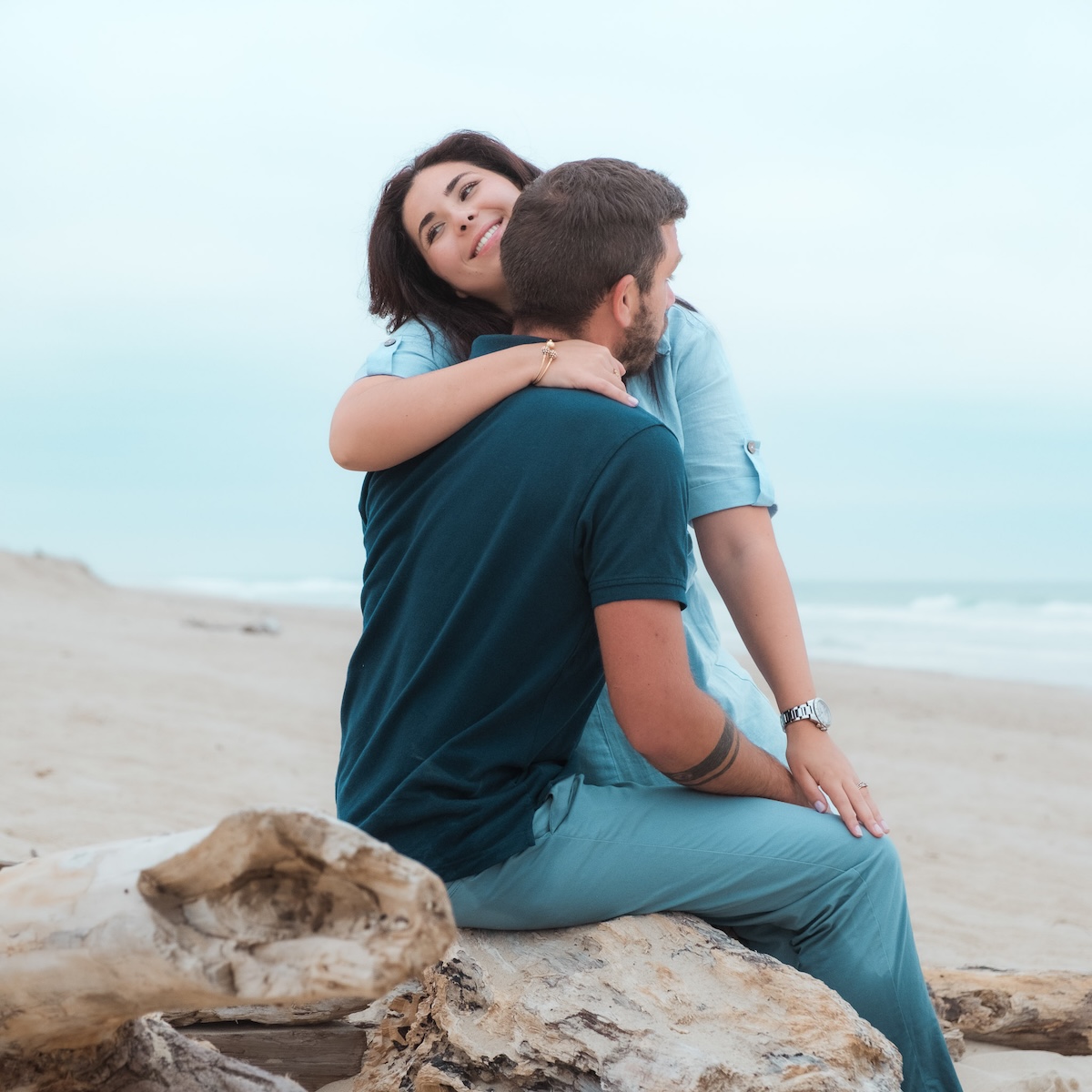 Couple sur la plage s'enlaçant assis sur le sable