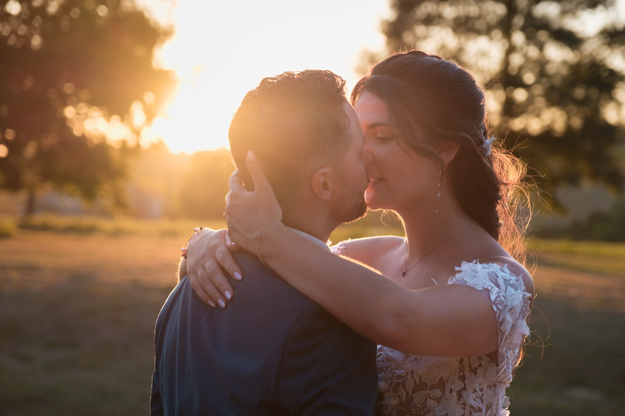 Mariés s'embrassant au coucher du soleil avec une lumière douce et chaude dans le parc d'un domaine de mariage